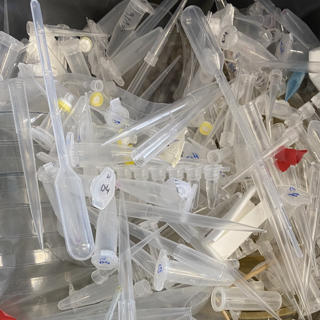Overhead view of trash can contents, piles of used plastic laboratory equipment such as pipette tips
