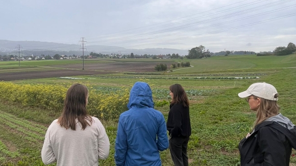 participants of the study week 2023 on an excursion, five people standing in front of a field